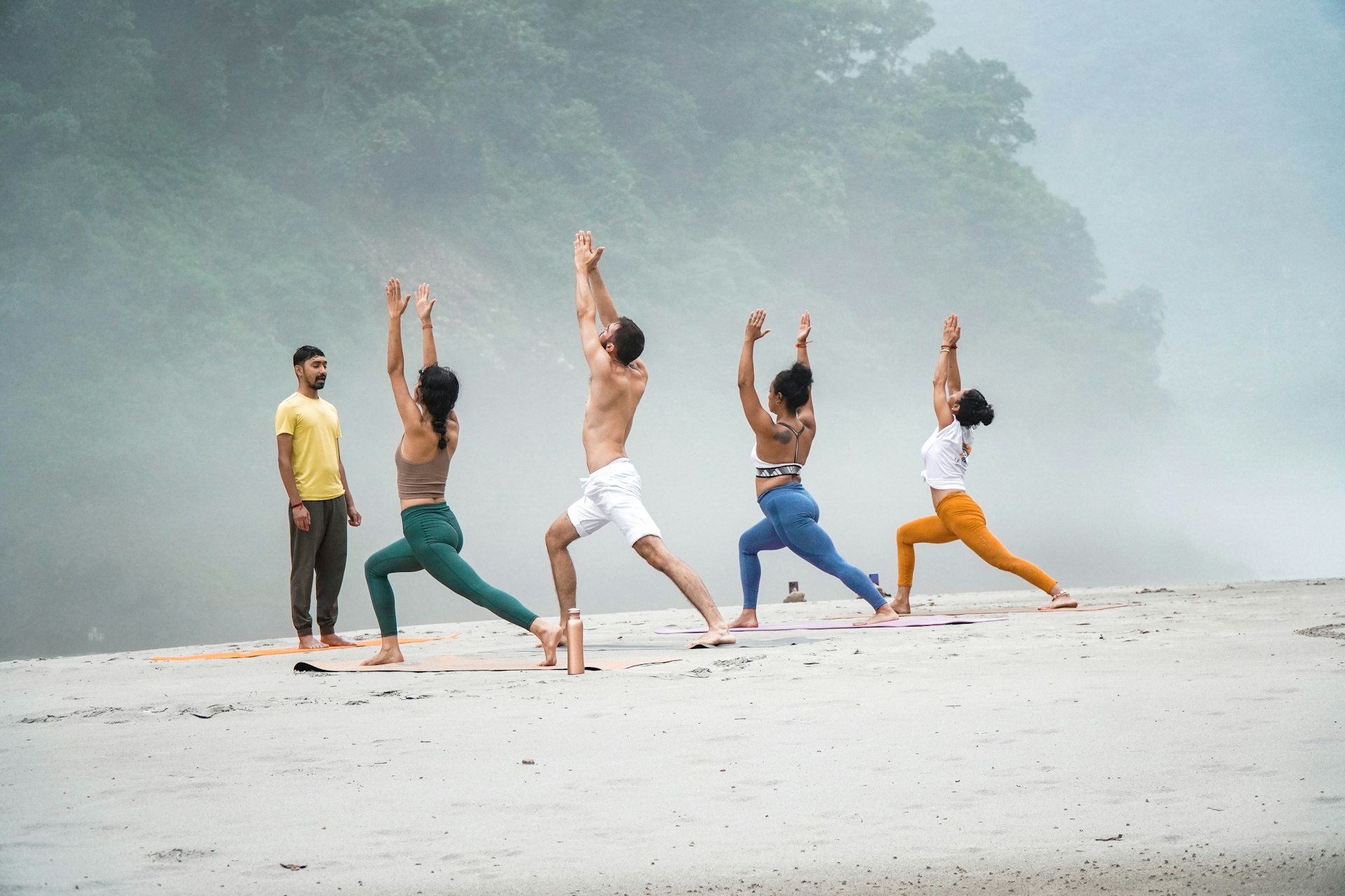 a group of people doing yoga on a beach